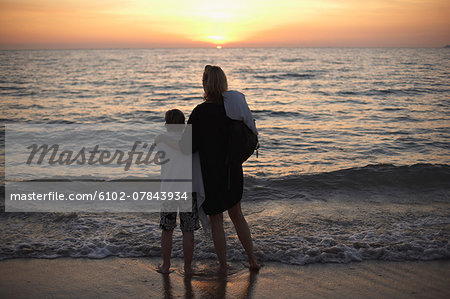 Mother with son watching sunset at sea