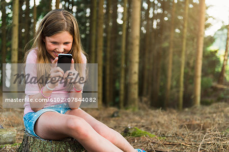 Girl with cell phone at forest