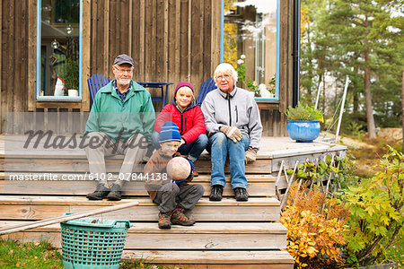Grandparents with grandchildren sitting in front of house
