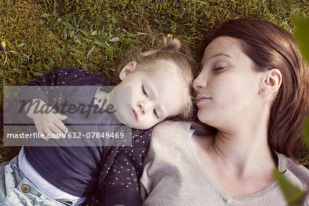 Mother and baby girl napping on grass