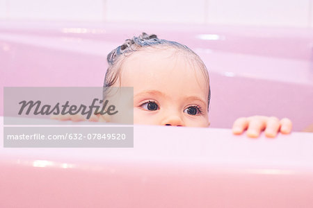 Baby peeking over side of bathtub