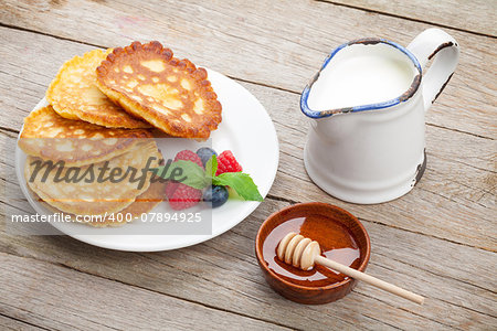 Pancakes with raspberry, blueberry, milk and honey syrup. On wooden table