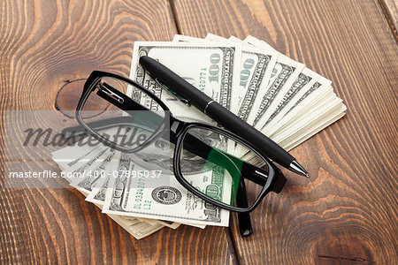 Money, glasses and pen on wooden table