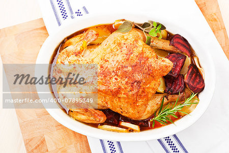 Luxurious golden baked chicken in white oval baking dish prepared for eating. Top view.