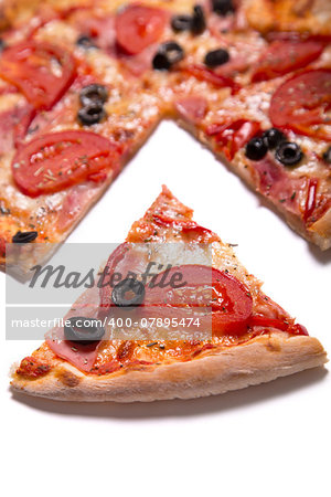 Tasty pizza with ham, tomatoes and olives with a slice removed, selective focus on slice