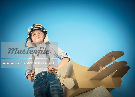 Little boy with a cardboard airplane outdoors
