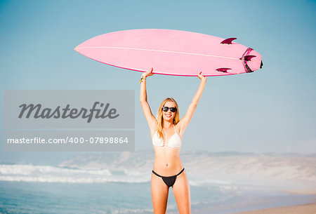 A beautiful surfer girl at the beach with her surfboard