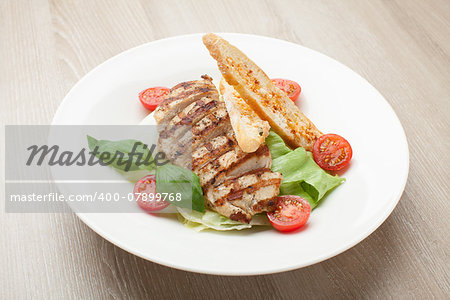 Gourmet delicious caesar salad with grilled beef meat fillet, romaine lettuce, cherry tomatoes,  cheese croutons and basil served in white plate