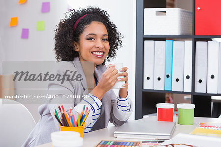 Portrait of smiling female interior designer with coffee cup sitting at office desk