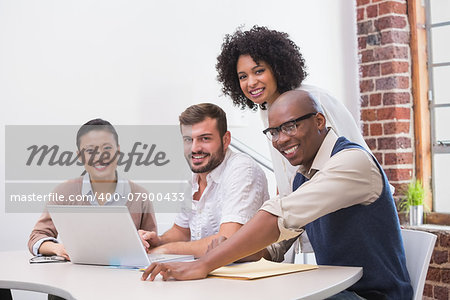 Happy creative business team using laptop in meeting at office