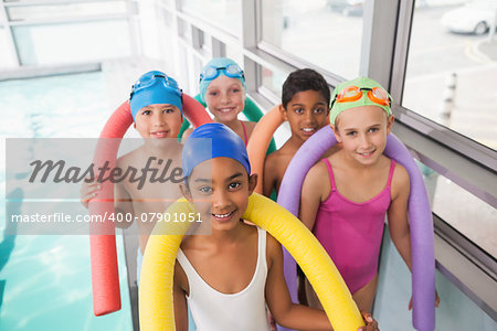 Cute swimming class smiling poolside at the leisure center