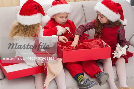 Festive little siblings opening a gift at home in the living room