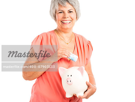 Portrait of a happy old woman putting money on  a piggy bank, isolated on a white background