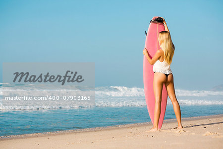 A beautiful surfer girl at the beach with her surfboard
