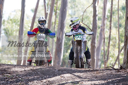 Two young male motocross riders chatting in forest