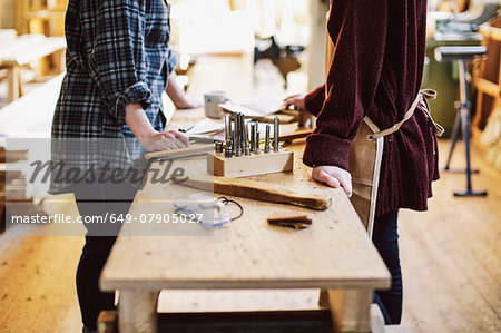 Cropped view of two craftswomen at workbench in pipe organ workshop