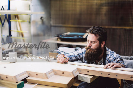 Cropped shot of mid adult craftsman measuring wood component in organ workshop