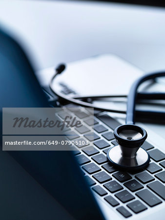 Stethoscope on top of laptop computer keyboard on doctors desk