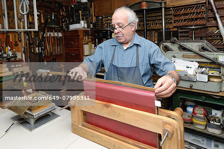 Senior man measuring book spine in traditional bookbinding workshop