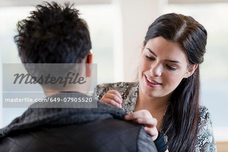 Young seamstress adjusting shoulder of customers jacket in workshop