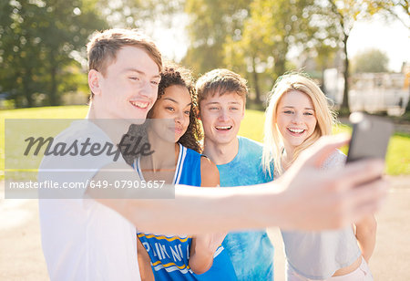 Four young adult basketball players posing for smartphone selfie