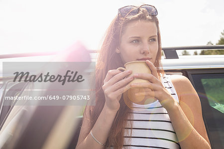 Young woman having coffee break on road trip