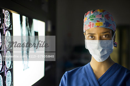 Portrait of young female doctor standing near screen with MRI image