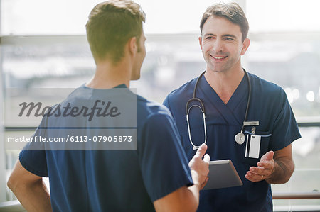 Two doctors talking, one holding tablet pc