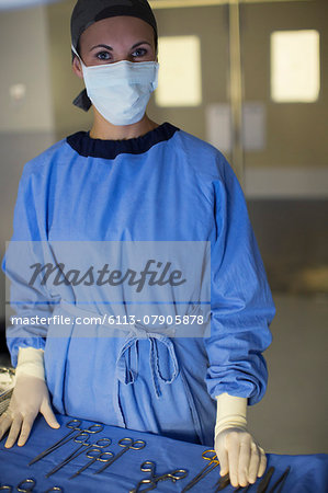 Portrait of masked surgeon with set of surgical instruments in operating theater