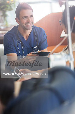 Doctor holding digital tablet, talking to patient undergoing medical treatment in outpatient clinic