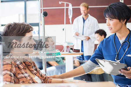 Female doctor holding clip board checking with female patient in outpatient clinic