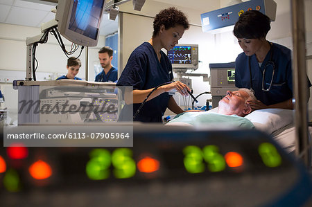 Doctors attending patient in intensive care unit, monitoring equipment in foreground