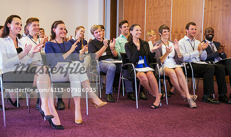 Business people watching presentation in conference room, clapping hands and smiling