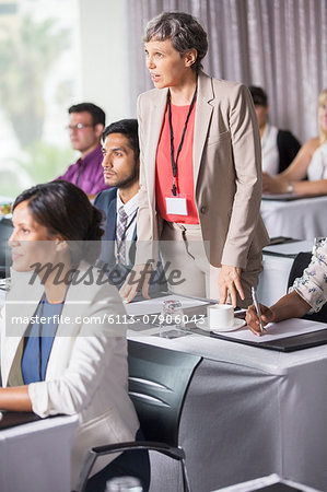 Businesswoman standing and asking question during presentation in conference room