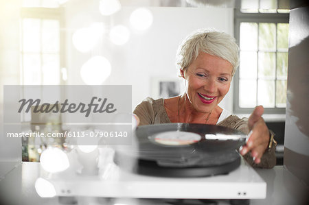 Older woman playing vinyl record on turntable