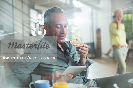 Older man using digital tablet at breakfast table Older man using digital tablet at breakfast table