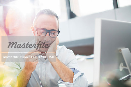 Businessman listening to earbuds at office desk Businessman listening to earbuds at office desk
