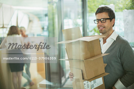 Businessman carrying cardboard boxes in office