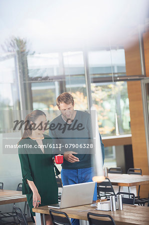 Business people using laptop in cafeteria