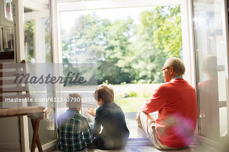 Grandfather and grandsons relaxing in doorway