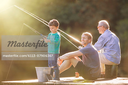 Boy, father and grandfather fishing on wooden dock