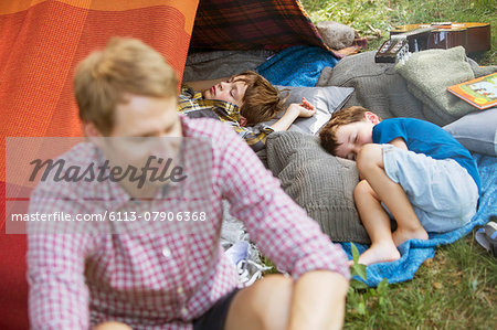 Father sitting with sleeping sons at camping tent