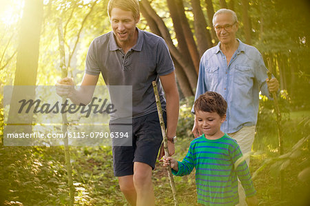 Boy, father and grandfather walking in forest