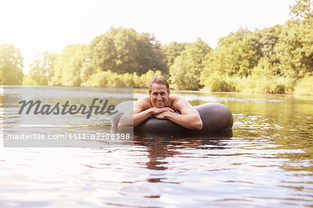 Man floating in inner tube in lake