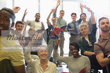 Smiling university students raising their hands at seminar