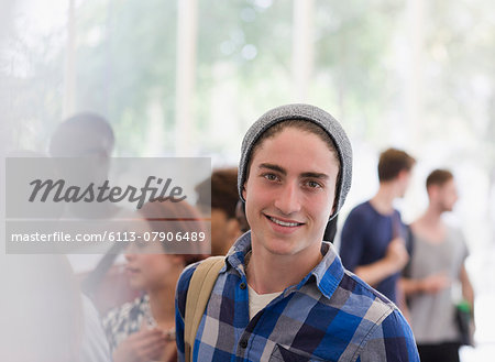 Portrait of smiling university student during break, people talking in background