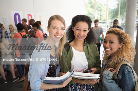 Portrait of university friends standing in corridor with books