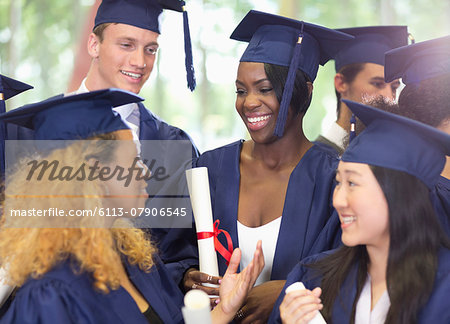 Group of smiling students wearing graduation clothes talking to each other