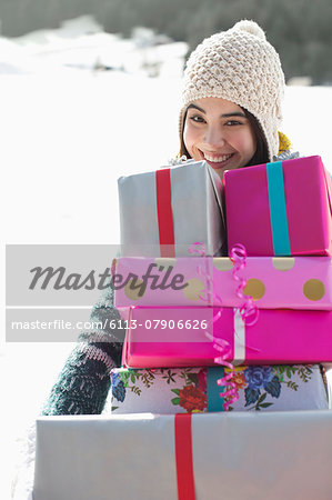 Portrait of smiling woman carrying stack of gifts