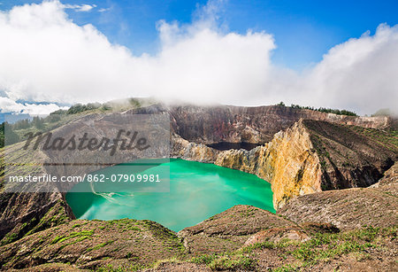 Indonesia, Flores Island, Moni. Low clouds lift to reveal two of the stunning crater lakes of Mount Kelimutu, a dormant volcano which last erupted in 1869.